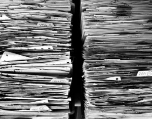 A black and white image of two stacks of paperwork, each file dated and organised in folders, showing a range of years.