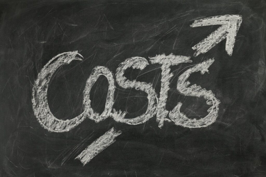 The word "costs" is written in large chalk letters on a blackboard, with an upward pointing arrow above it, suggesting rising costs—a challenge hospitals like the NHS face while seeking ways of cutting costs.