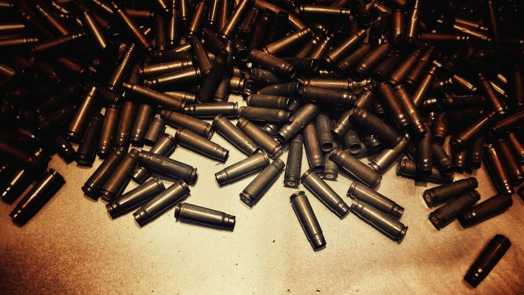 A large pile of empty brass bullet casings scattered on a flat surface, evoking the aftermath of war.