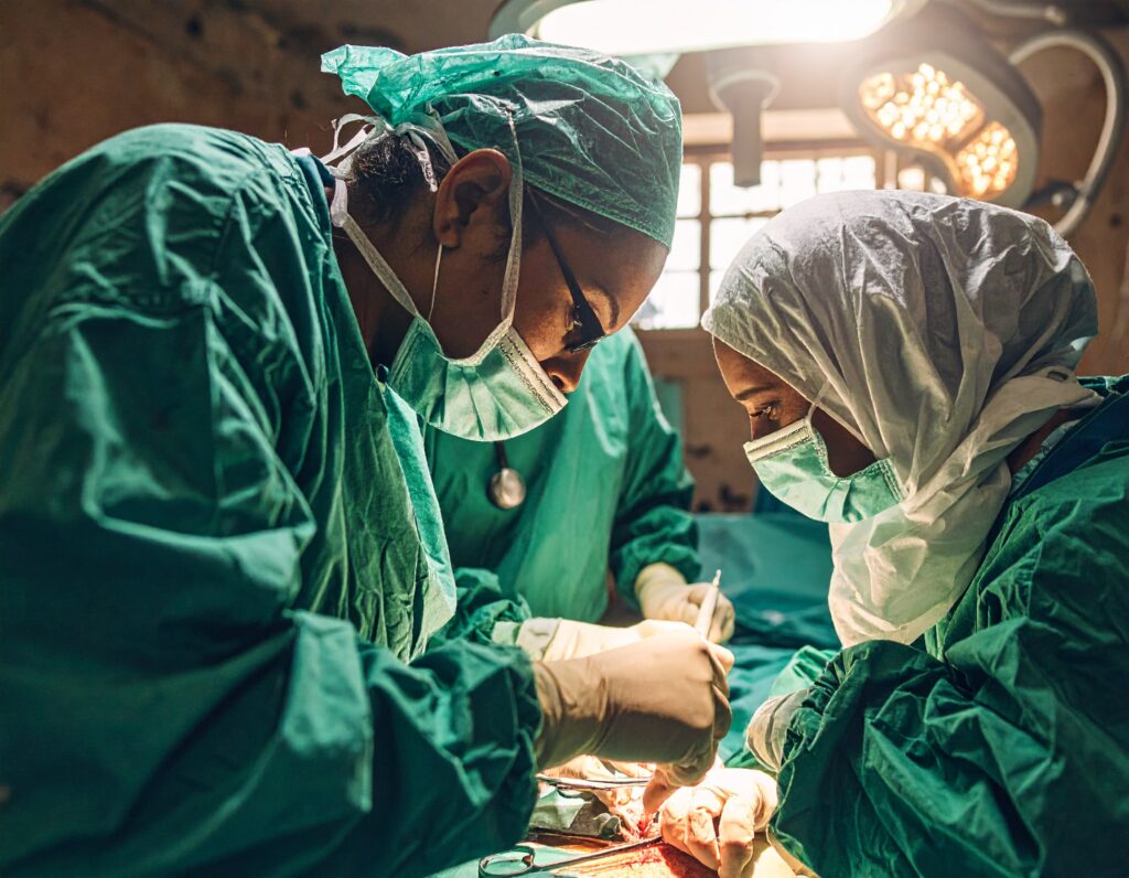 urgeons in green scrubs performing a delicate operation in a low-lit hospital setting.