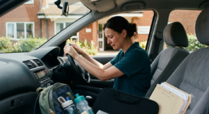 A working mother sits in her parked car outside a UK care home, overcome with emotion after visiting her mother with dementia while balancing work and family responsibilities. Andy Burnham social care reform