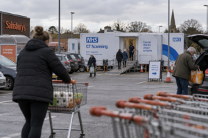 NHS mobile CT scanning unit in a supermarket car park, with shoppers and trolleys in the foreground as patients enter the unit. NHS prevention success